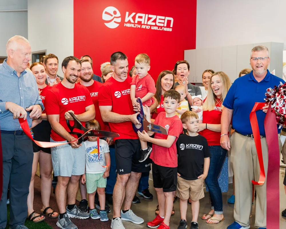 Bryan and Deana Ladd cutting the ribbon at the Kaizen Health and Wellness grand opening in Urbandale, IA, surrounded by family and community